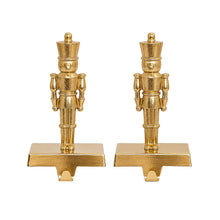 Pair of gold nutcracker stocking holders with wide bases and hooks