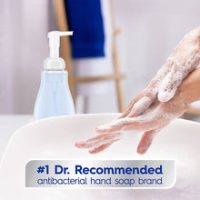 Foaming antibacterial hand soap dispenser with lathered hands over sink