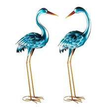 Two heron metal statues with teal wings, orange beaks, gold wire legs, and round feet.