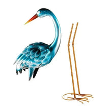 Blue heron statue pair—teal metal bird with orange beak, curved neck, and gold wire legs.