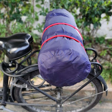 Red bungee cords with black hooks securing a wrapped load on handlebars