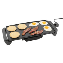 Electric griddle cooking surface with bacon and fried eggs on non-stick plate