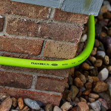 Lime-green garden hose connected to brick wall spigot with metal fitting