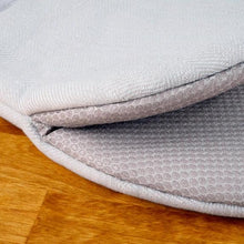 Padded kitchen potholder with white outer fabric and gray backing, folded