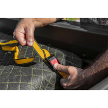 Hand adjusting ratchet tie-down strap on a cargo cover