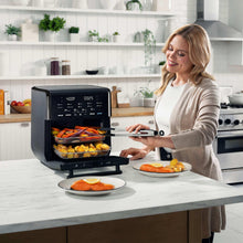 Black air fryer oven with open door and tray of food on kitchen counter