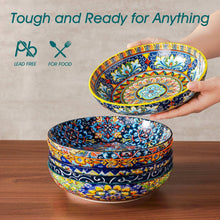 Hand holding a colorful ceramic pasta bowl, blue and yellow ornate floral design