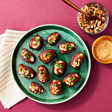 Stuffed Medjool dates on a green plate with chopped toppings