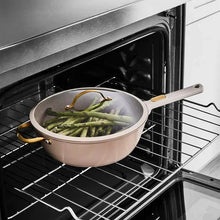 Taupe sauté pan with green vegetables on oven rack; gold handles and white grip