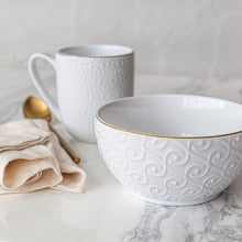 White stoneware bowl with embossed swirl pattern and thin gold rim