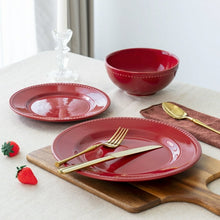 Red stoneware dinnerware set with plates and bowls, dotted edge detail