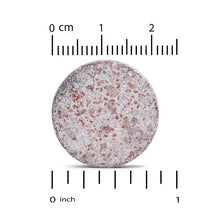 Chewable tablet sample, round speckled surface with inches size marks
