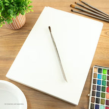 Natural white watercolor paper pad with blank sheet, brushes, and color palette