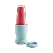 Teal blender base holding red smoothie with teal lid