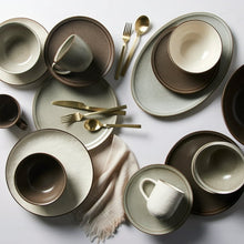 Mixed stoneware plates and bowls in cream and dark olive tones with gold-tone edges
