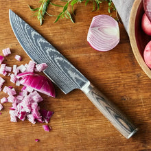 Chef's knife with dark Damascus-style blade and wood handle, with vegetables on a board