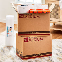 White bubble wrap roll beside medium shipping boxes for packing and cushioning