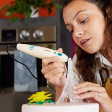 White Chef 3D pen held to add colorful candy to a frosted cake