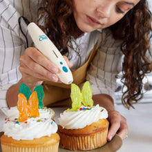 White Chef 3D pen adding colorful candy to a frosted cupcake