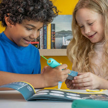 Children using a teal 3D pen to decorate pieces on a tabletop