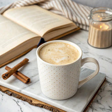 White coffee mug filled with creamy light-brown beverage on a tray