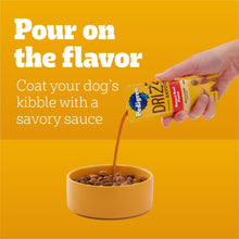 Savory sauce pouch pouring onto dog kibble in a bowl
