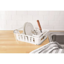 White dish drying rack with utensil holder, plate supports, and draining tray on countertop