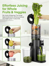 Black cold press juicer with hands feeding whole fruits and leafy vegetables into chute.