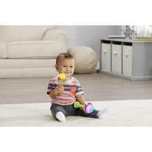 Baby sitting and holding a small colorful maraca with a translucent rattle head