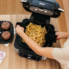 Electric grill basket filled with golden fries, hands lifting the tray