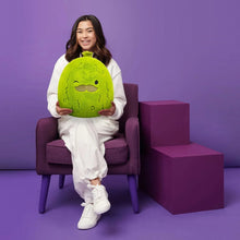Green pickle plush toy with mustache held by a child