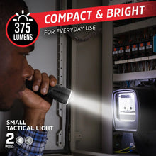 Small black tactical flashlight shining light from a doorway
