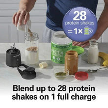 Portable blender base with clear jar on table beside protein shake ingredients