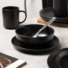 Black stoneware serving bowl with spoon and forks, plus mugs