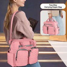Pink diaper bag tote worn on shoulder with front zip pockets and crossbody strap