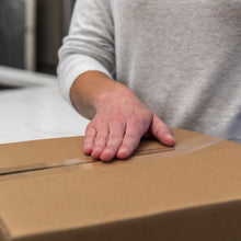 Man smoothing clear tape over cardboard box seam