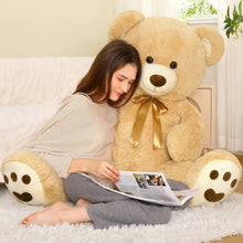 Tan teddy bear plush with gold neck bow and stitched smiling face