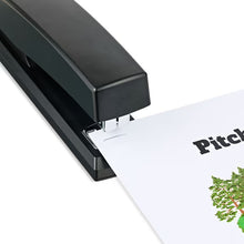 Black desktop stapler pressing through paper, close-up of stapling nose