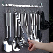 Stainless utensil rack with hooks and hanging cooking tools, including tongs and spatulas