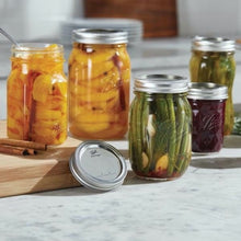 Set of wide-mouth glass mason jars with metal lids and bands, filled with mixed preserves