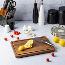 Acacia wood cutting board with triangle anti-slip grips, shown with sliced lemons on top
