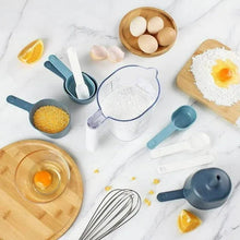 Blue measuring cups and scoops with white whisk and measuring pitcher