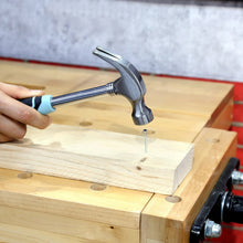 Claw hammer driving a nail into a wooden board during basic repairs