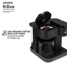 Black Keurig dual coffee maker with pod area open and used grounds visible