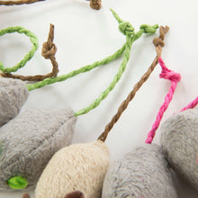 Close-up of plush cat mouse toys with braided string tails in green, tan, and pink.