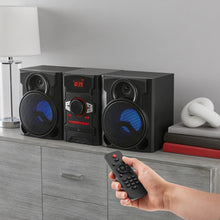 Black stereo speaker system on shelf with remote control and glowing display