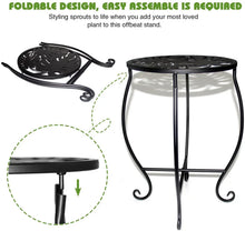 Black tall metal plant stand with round perforated top and curved scroll legs.