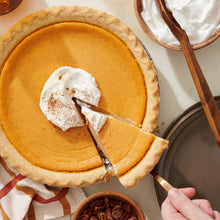 Sweet potato pie being sliced, topped with whipped cream
