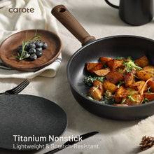Black nonstick saute pan with wooden handle, filled with roasted vegetables