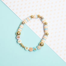 Beaded bracelet with striped beads and gold-tone spacers, letter beads spelling KIND
